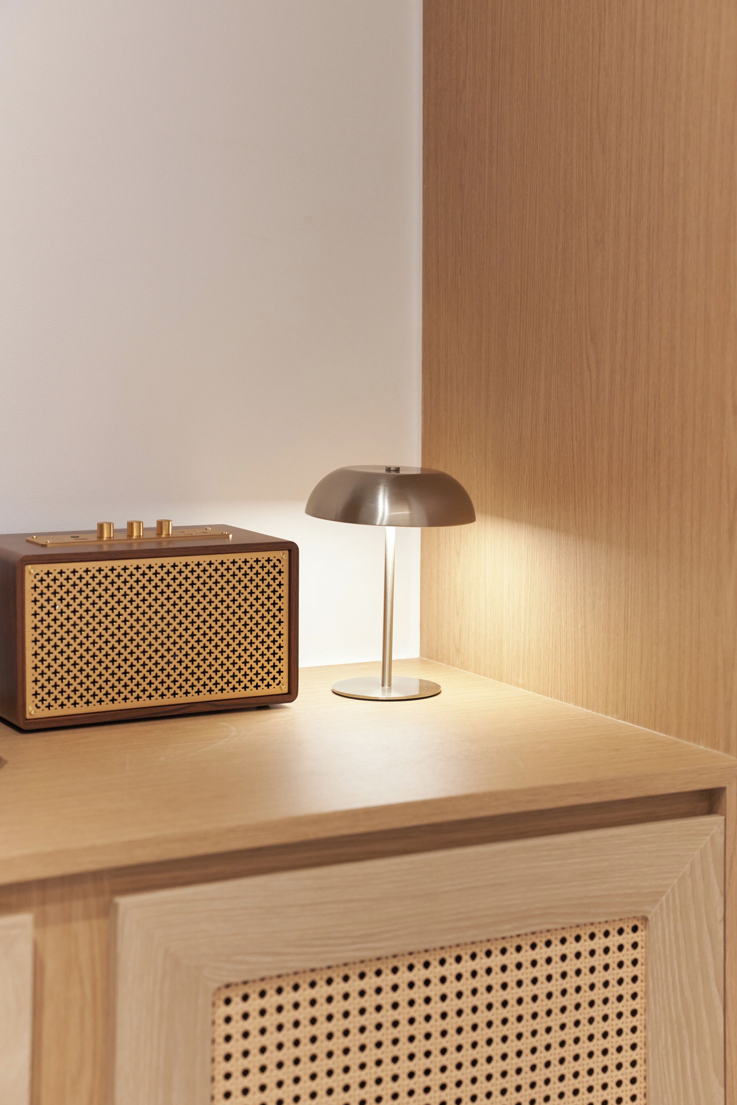 A wooden desk with a radio and a lamp.