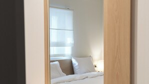 Un dormitorio moderno con cabecera de cama de madera, una mesita de noche y un espejo que refleja la habitación.
