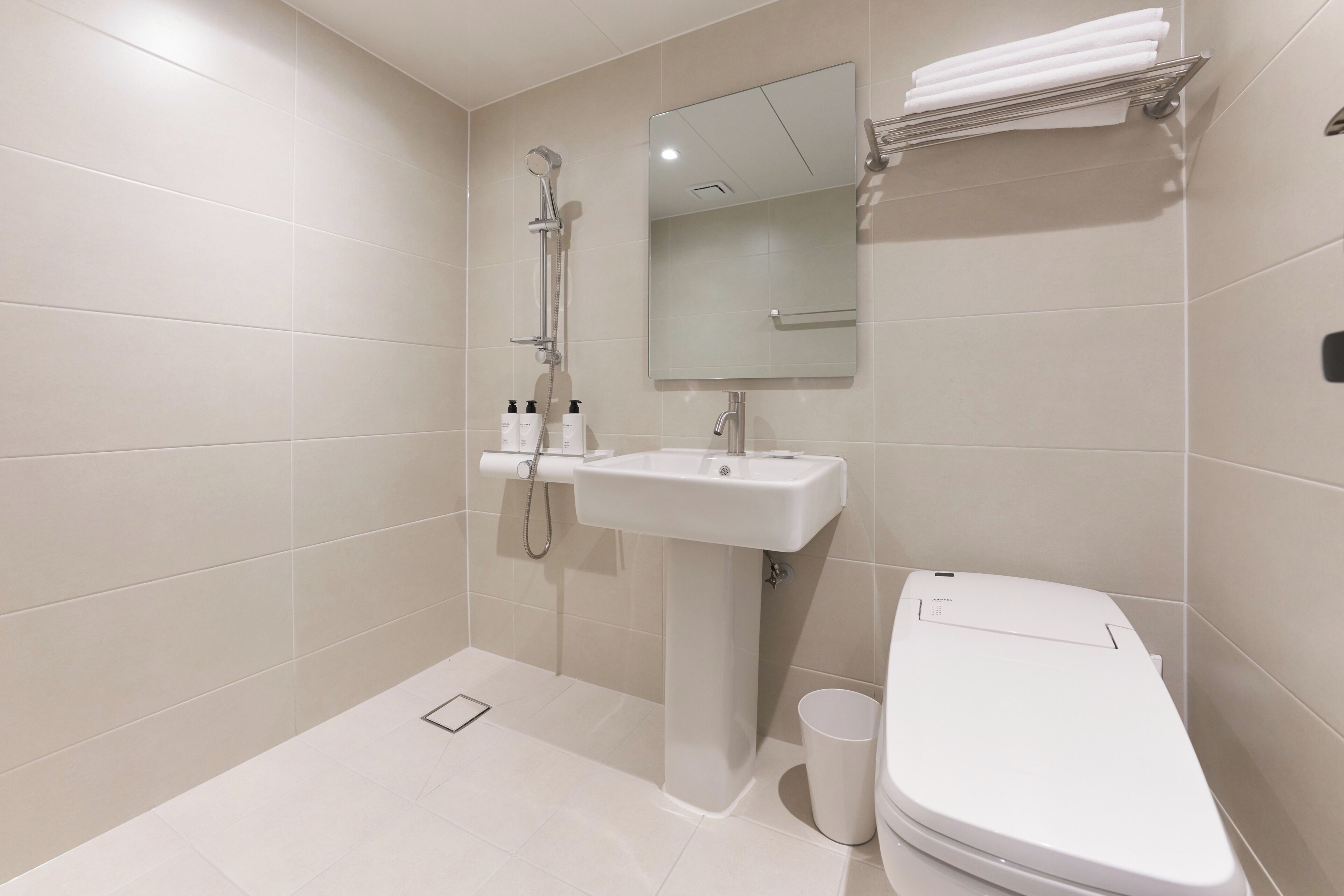 A modern bathroom with a shower, sink, mirror, and toilet.