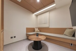 A modern room with a round table, a bench with cushions, and a wall-mounted light fixture. - Hohe City Dongdaemun (Seoul)