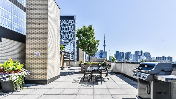Terraza en la azotea con mobiliario exterior, una parrilla y vistas al horizonte de la ciudad.