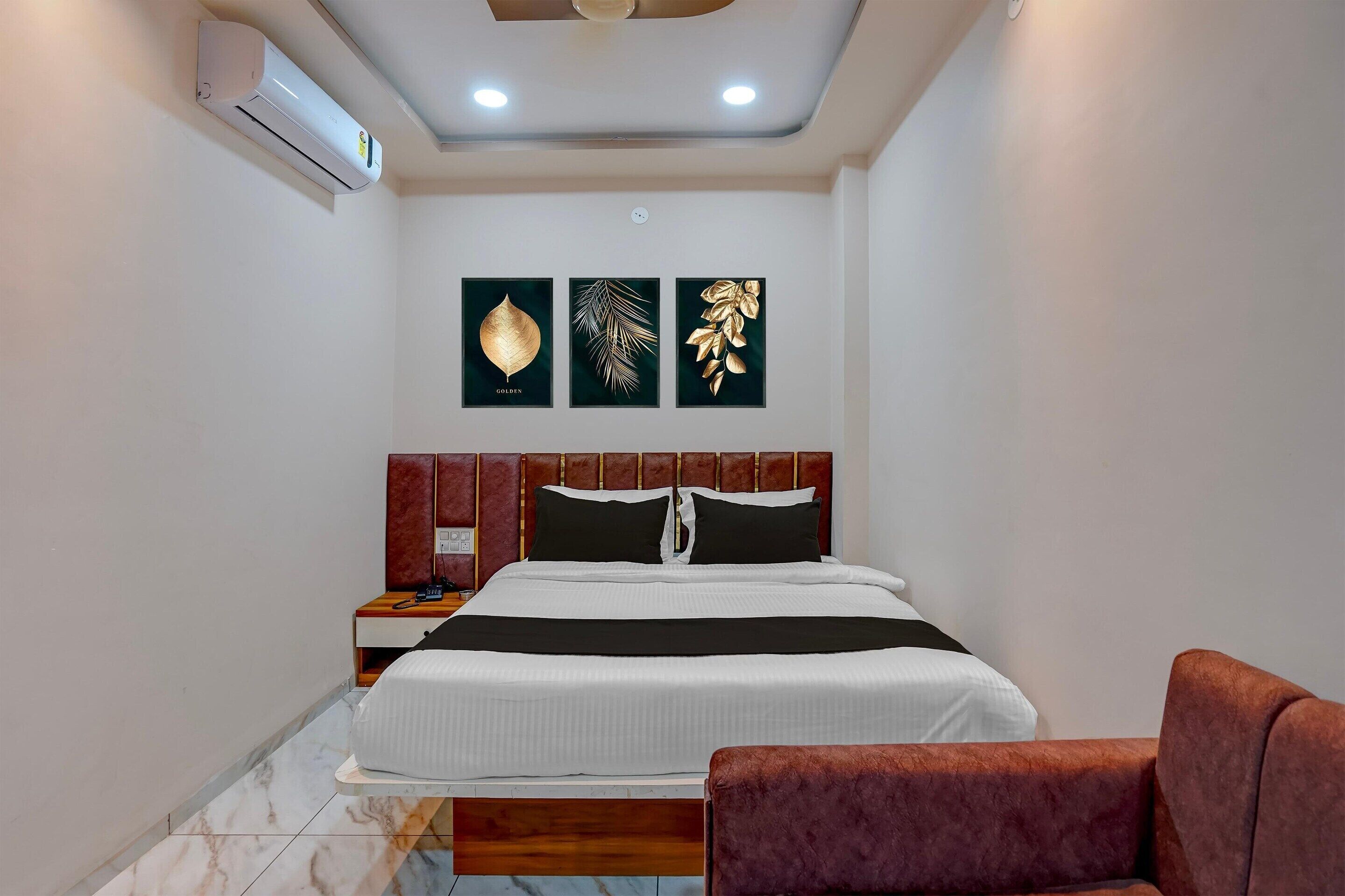 A bedroom with a bed, a nightstand, a red upholstered chair, and wall-mounted artwork.