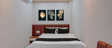 A bedroom with a bed, a nightstand, a red upholstered chair, and wall-mounted artwork.
