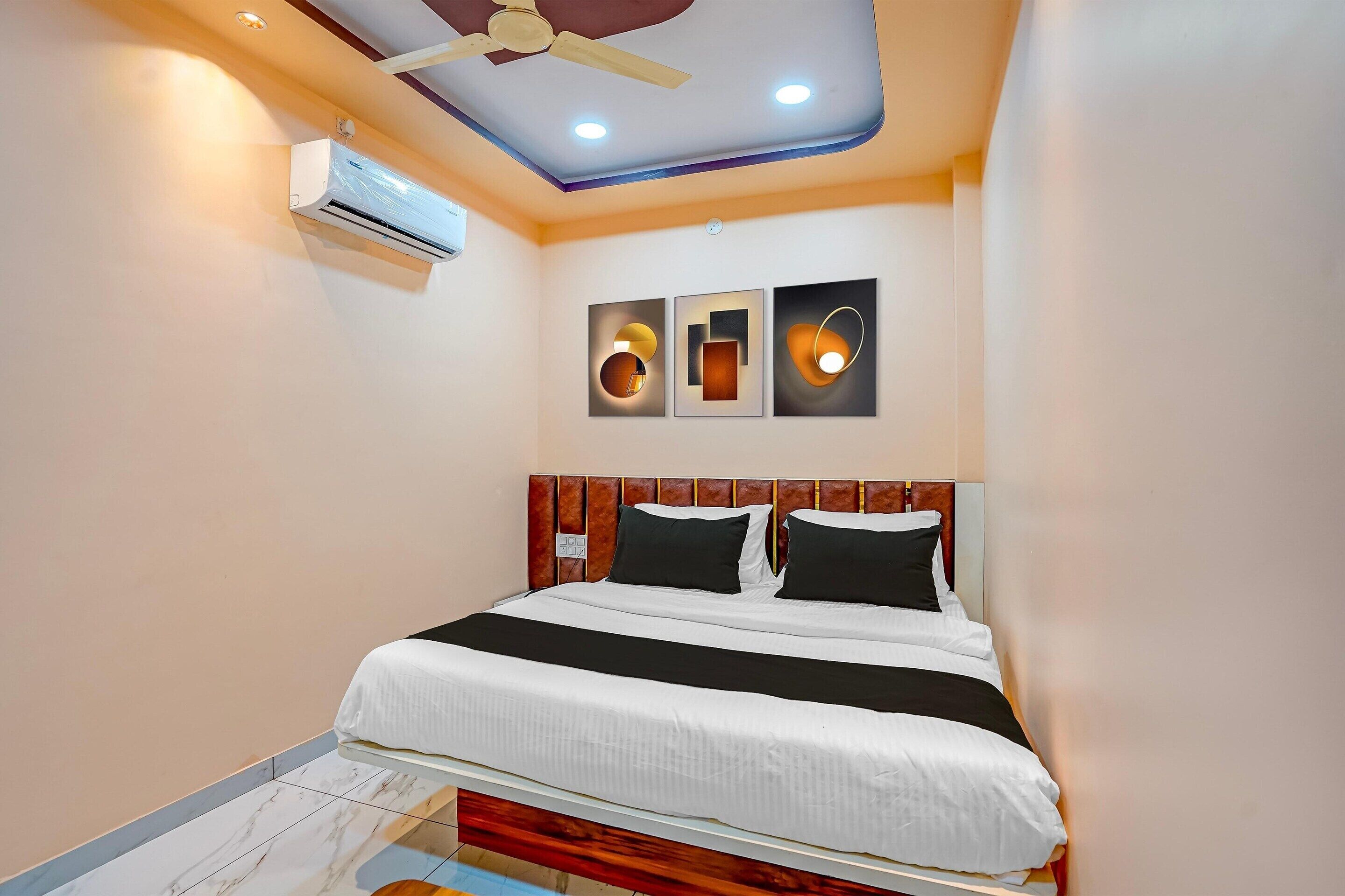 Ein Hotelzimmer mit Bett, Deckenventilator, Einbauleuchten, Wandklimaanlage und Kunstwerken.