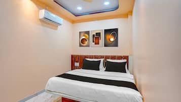 Habitación de hotel con cama, ventilador de techo, luces empotradas, aire acondicionado de pared y obras de arte.