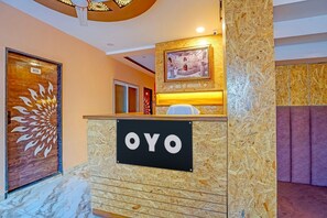 A reception desk with a sign reading 'OYO' and a framed picture above it. - Classic Hotel Ramashray Palace (Ujjain)