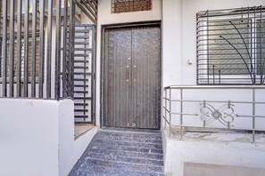 A closed metal gate, a set of stairs leading to a door, and a metal railing. - Classic Hotel Ramashray Palace (Ujjain)