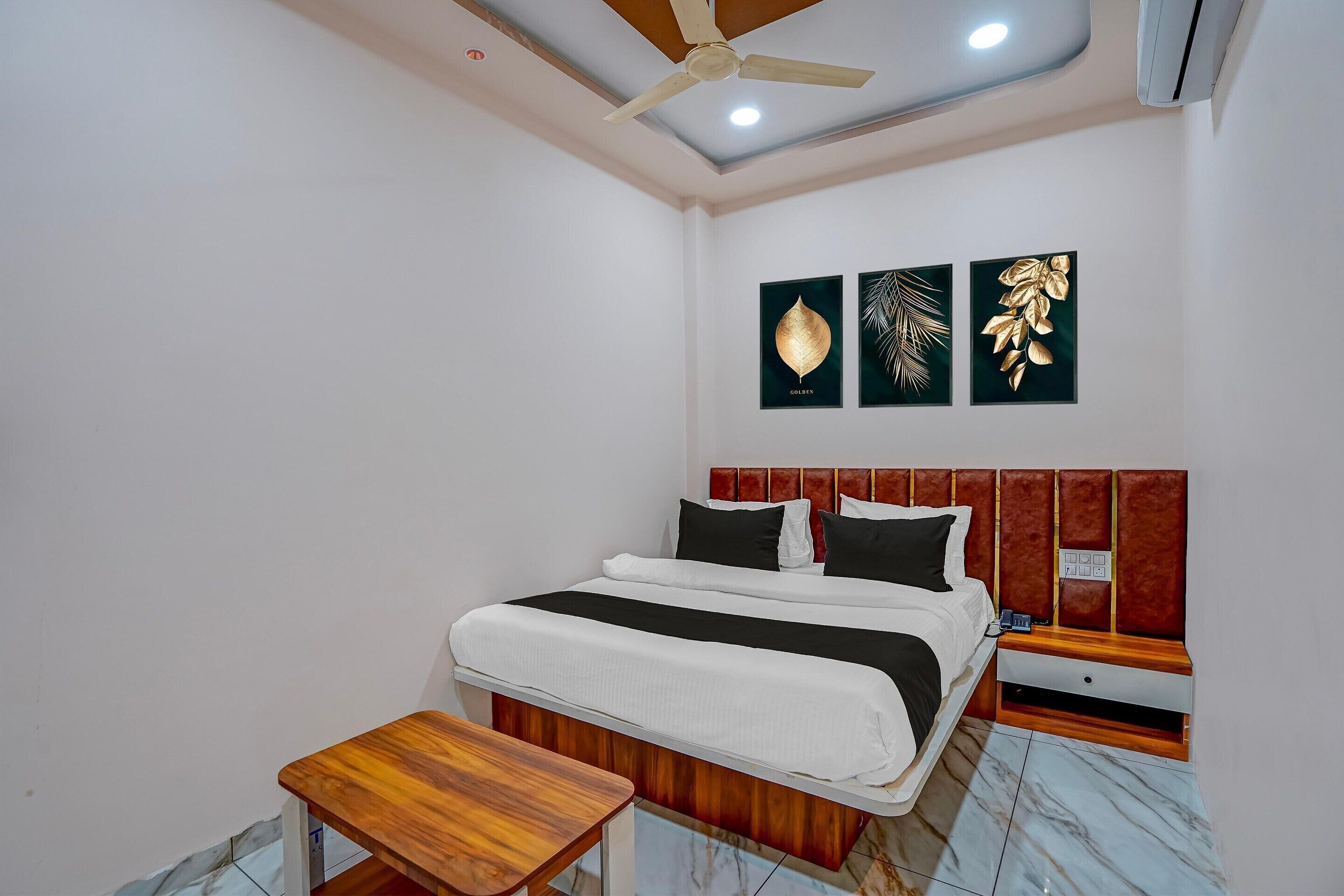 A bedroom with a bed, bedside table, nightstand, ceiling fan, and wall art.