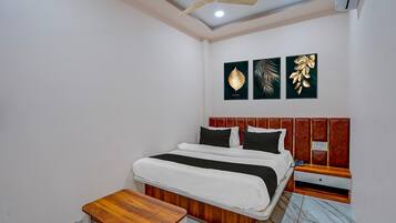 A bedroom with a bed, bedside table, nightstand, ceiling fan, and wall art.