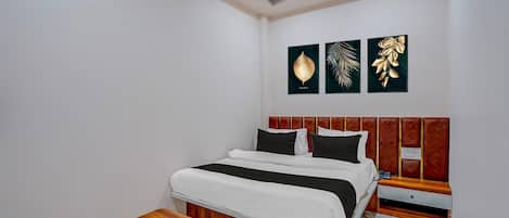 Un dormitorio con cama, mesita de noche, ventilador de techo y decoración en la pared.