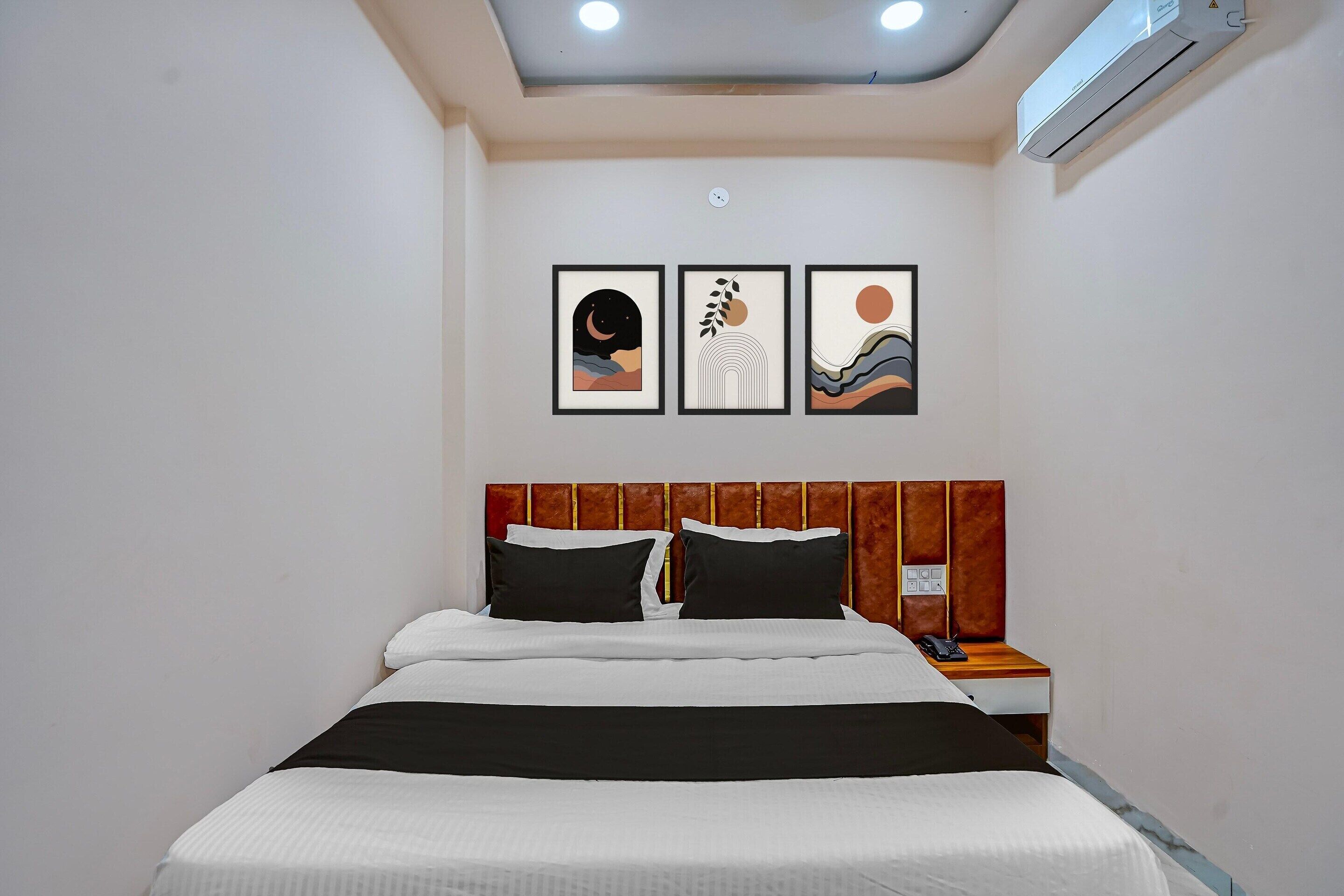 Une chambre d’hôtel avec un lit, une table de chevet et trois œuvres d’art encadrées accrochées au mur.