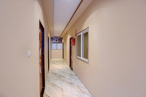 A hallway with a marble floor, doors, and a fire extinguisher. - Classic Hotel Ramashray Palace (Ujjain)