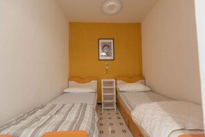 Un alojamiento pequeño y de una sola habitación con dos camas, una estantería y un cuadro en la pared.