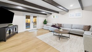 A modern living room with a sofa, coffee table, TV, and a cabinet. - San Diego Family Getaway, 4BR Home Near Beaches & Balboa (Spring Valley)