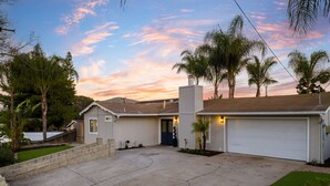 A residential house with a garage, a driveway, and a small front yard with a lawn and a few trees. - San Diego Family Getaway, 4BR Home Near Beaches & Balboa (Spring Valley)