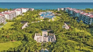 Un complex turístic amb diversos edificis, una zona de piscina central i vegetació abundant.