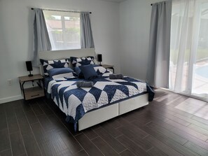 Un dormitorio con cama, mesitas de noche, lámpara y ventana con cortinas.