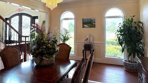 Comedor con candelabro, ventanas amplias y plantas en macetas.