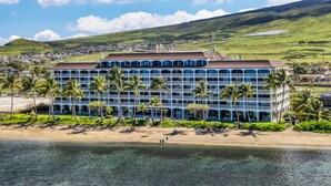 A large hotel with multiple floors, a beach in the foreground, and a hilly landscape in the background. - Ocean view studio in vibrant West Maui for 2.-Lahaina Shores 511 (Lahaina)