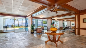 A spacious lobby with a large glass door leading to a pool area, wooden ceiling beams, and a central table with a bowl. - Ocean view studio in vibrant West Maui for 2.-Lahaina Shores 511 (Lahaina)
