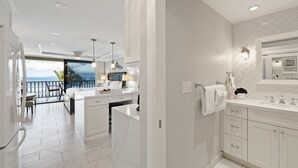 A modern kitchen with a large island, a dining area with a view, and a spacious bathroom with a herringbone tile backsplash. - Ocean view studio in vibrant West Maui for 2.-Lahaina Shores 511 (Lahaina)