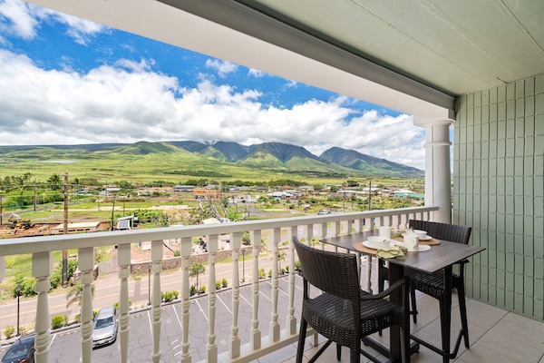 Furnished fifth-floor lanai with dining set overlooking West Maui Mountains.