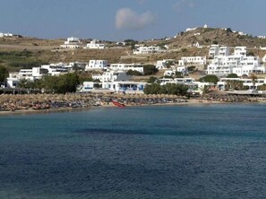 Un pueblo costero con edificios blancos, una playa y una colina al fondo.
