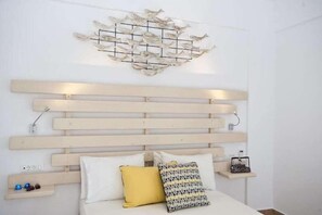 Un dormitorio con cabecera de madera, lámpara de pared y mesitas de noche con adornos.