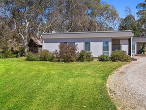 A two-story house with a front porch, a gravel driveway, and a well-maintained lawn.