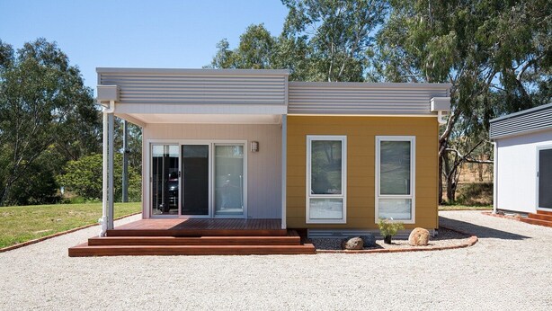 Une maison moderne à deux étages, dotée d’un porche abrité, d’un garage et d’une allée gravillonnée.