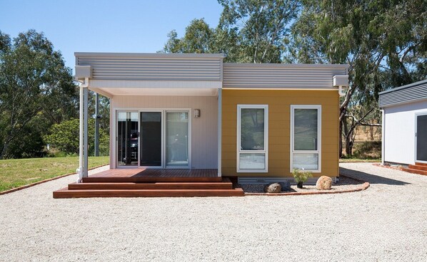 Ein modernes, zweistöckiges Haus mit einer überdachten Veranda, einer Garage und einem Schotterweg.