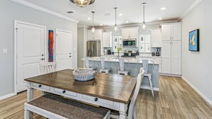 A modern kitchen with white cabinetry, a wooden dining table, and pendant lighting. - New Listing!| Lost Key| Dogs welcome| Two pools| Private Beach Club| Tennis| Free Golf (Pensacola)