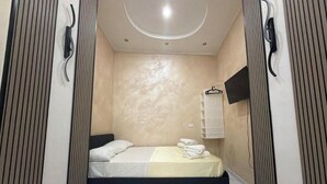 Ein Schlafzimmer mit einem Bett, einem Handtuchhalter und einem am Wand montierten Fernseher.