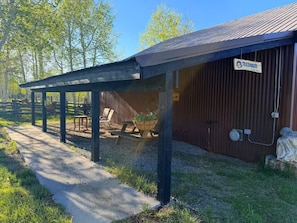 A covered outdoor area with a picnic table and chairs, a wooden fence, and a building labeled 'TREEHOUSE.' - The Treehouse Cabin! (Montrose)