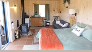 Een knus kamer in chaletstijl met een bed, een sofa, een open haard en een kitchenette.