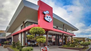 A Jollibee restaurant with a distinctive red and white logo, surrounded by greenery and a clear sky. - Cozy 1Bedroom Near Mactan Cebu International Airport (Lapu-Lapu)