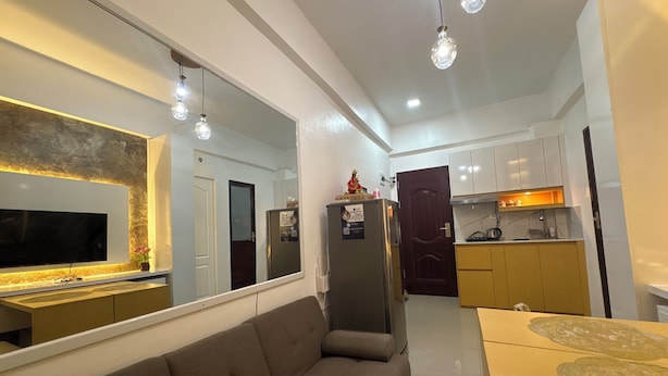 A modern living room with a large flat-screen TV, a sofa, and a dining table. - Cozy 1Bedroom Near Mactan Cebu International Airport (Lapu-Lapu)