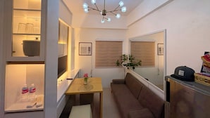 A compact living space with a kitchenette, a dining area, a seating area, and a ceiling light fixture. - Cozy 1Bedroom Near Mactan Cebu International Airport (Lapu-Lapu)