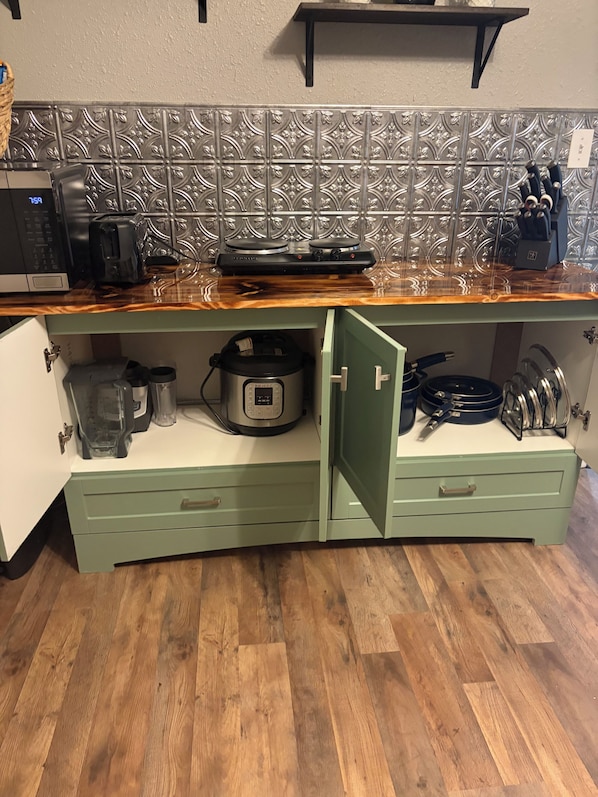Une cuisine équipée d’un four à micro-ondes, d’un grille-pain, d’un cuiseur à riz et d’un plan de travail en bois.