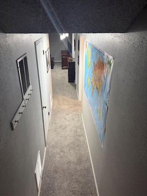 Un couloir avec une bouche d’aération, une carte accrochée au mur et un bureau avec un ordinateur.