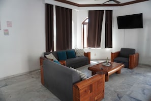 A living room with a sofa, armchairs, a coffee table, and a TV mounted on the wall. - Hostal Mardan Puerto Vallarta Aeropuerto (Puerto Vallarta)