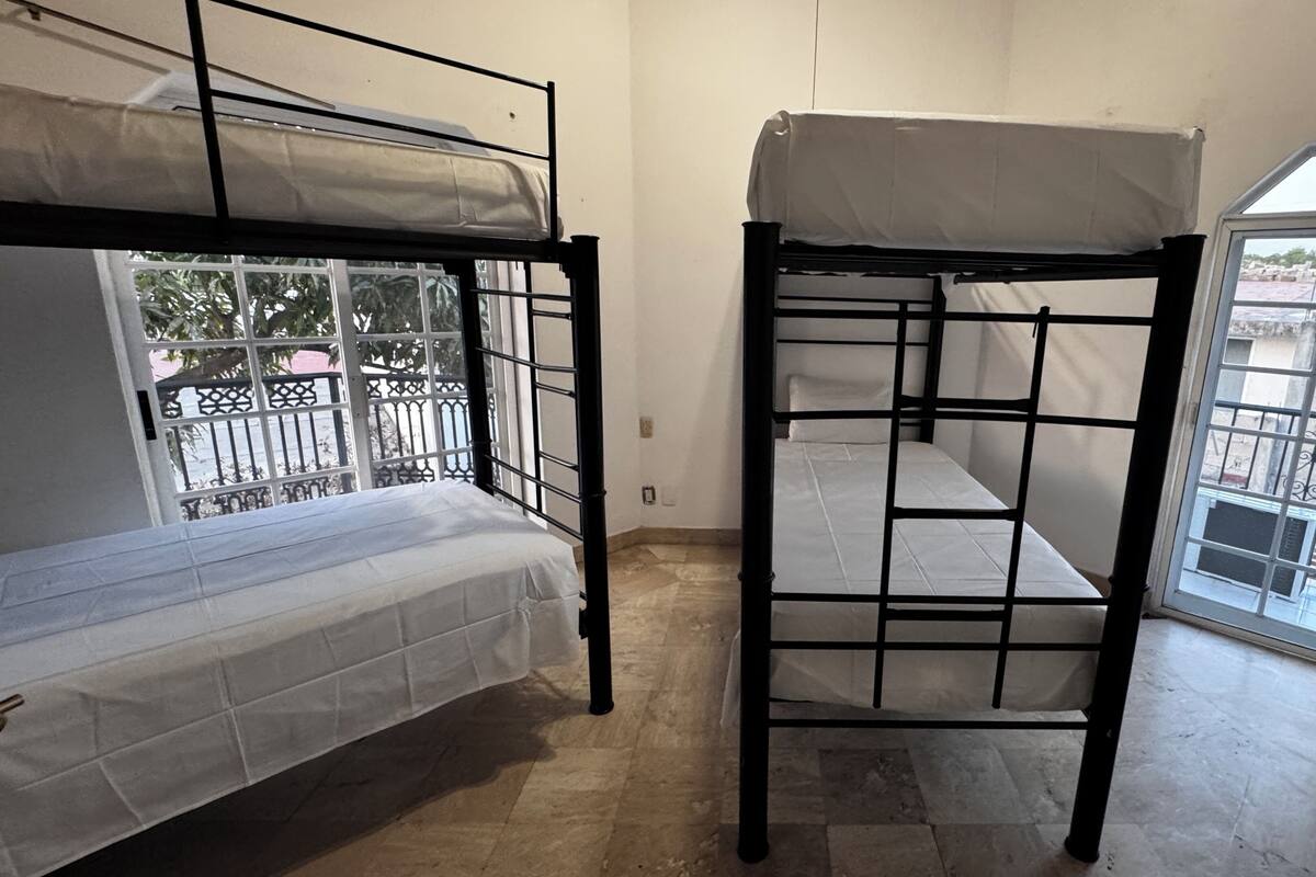 Un dormitorio con literas, una ventana con vistas al exterior y una puerta que da a un balcón.