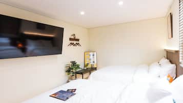 Una camera d'albergo con un letto, una televisione, un piccolo tavolino con una pianta e una mensola a parete.