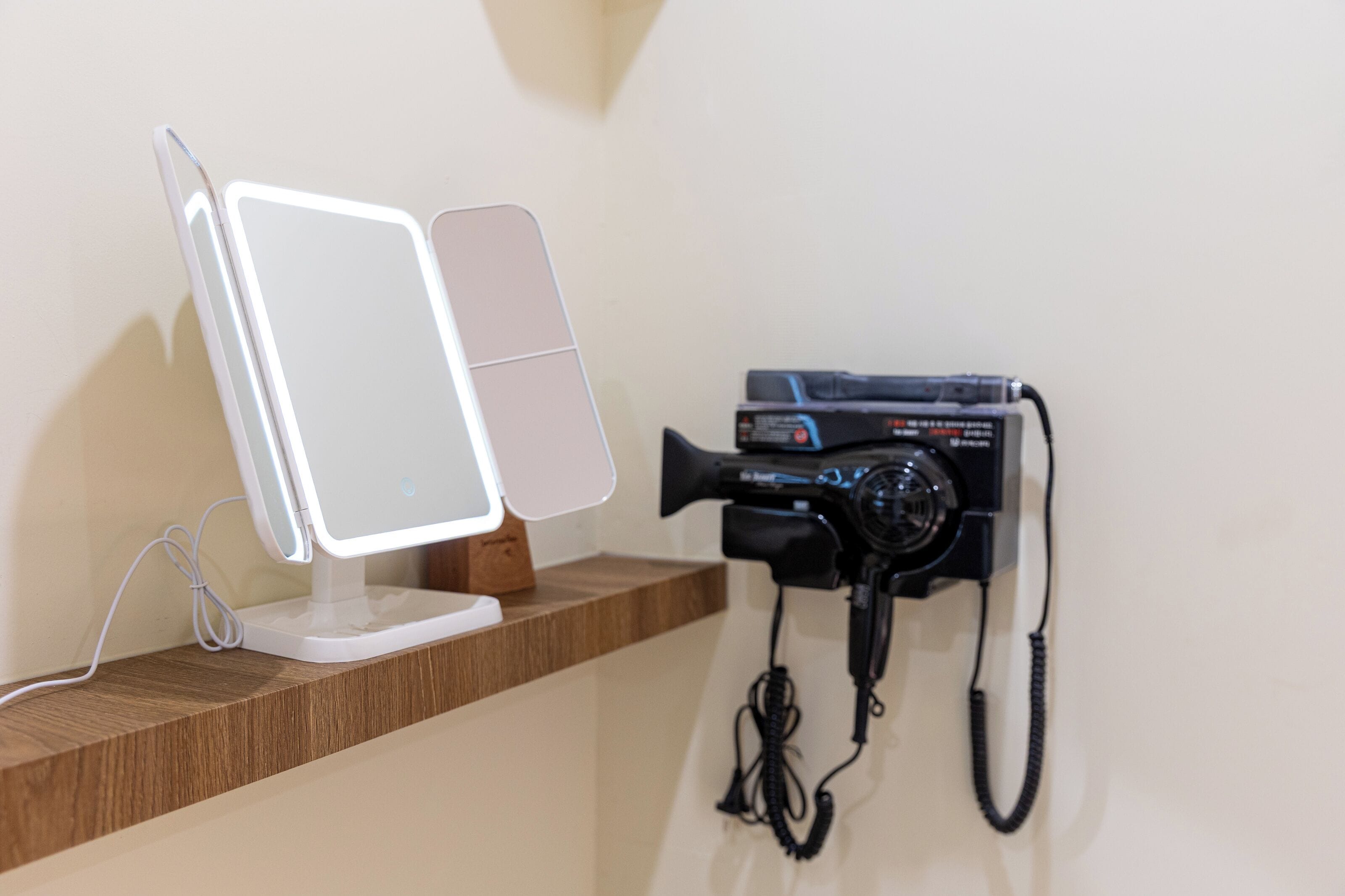 Uma escrivaninha com um monitor de computador e um telefone preto.