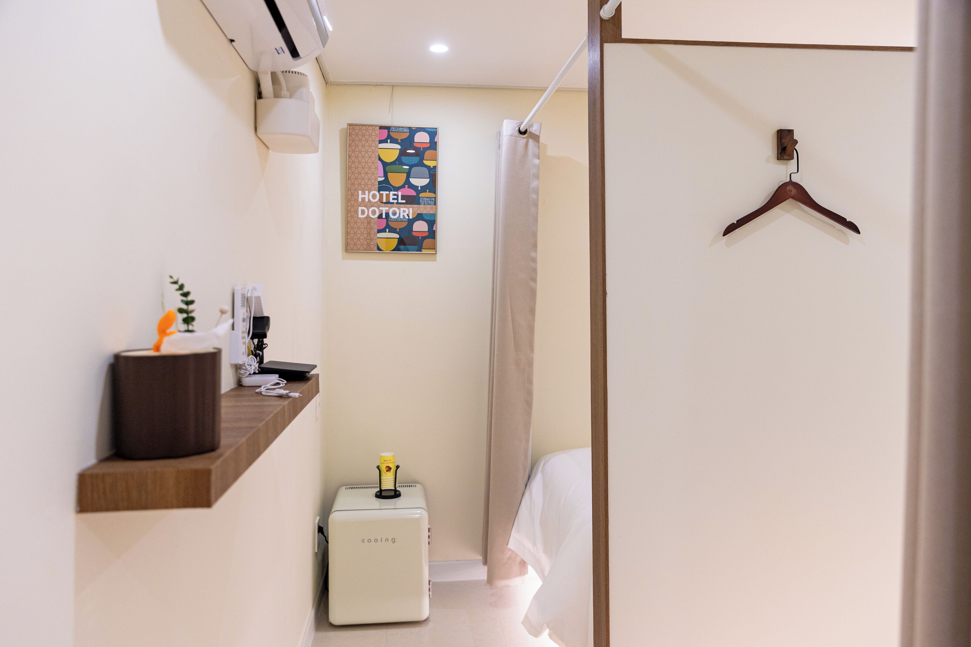 Habitación de hotel con repisa de madera, unidad de ventilación pequeña, toalla colgada y cortina de ducha.