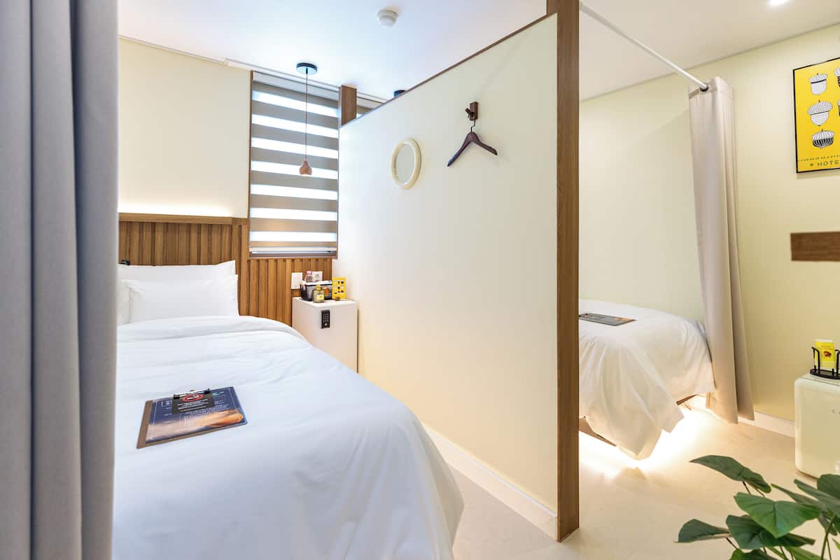 Una habitación de hotel con cama, mesita de noche y un escritorio pequeño con silla.