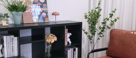 A black bookshelf with books, a vase with flowers, a framed picture, and a small white figurine.