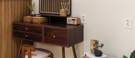 Un escritorio de madera con un espejo, una radio y una planta pequeña.