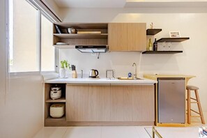 A modern kitchen with built-in appliances, wooden cabinetry, and a small island with seating. - Comfortable, Cozy  Studio Unit  with pool and garden view and 15 mins to airport (Cebu)