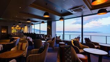 A modern lounge with comfortable seating, large windows, and a view of the water.
